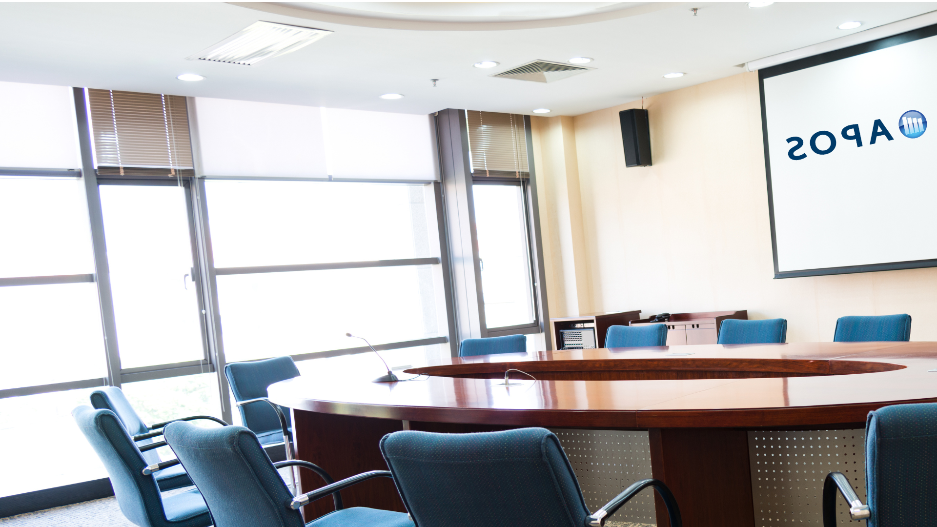 empty boardroom table, windows, APOS logo on screen