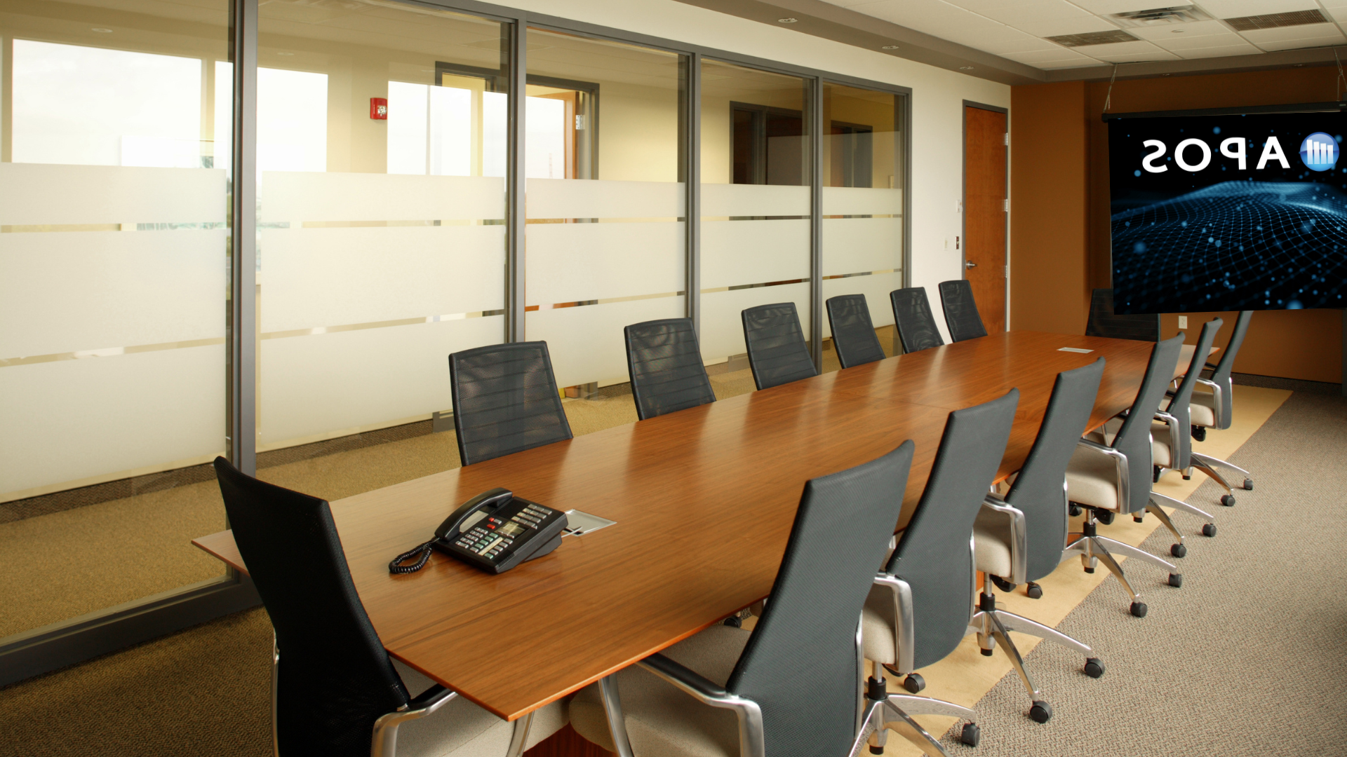 empty long boardroom table, APOS logo on back screen